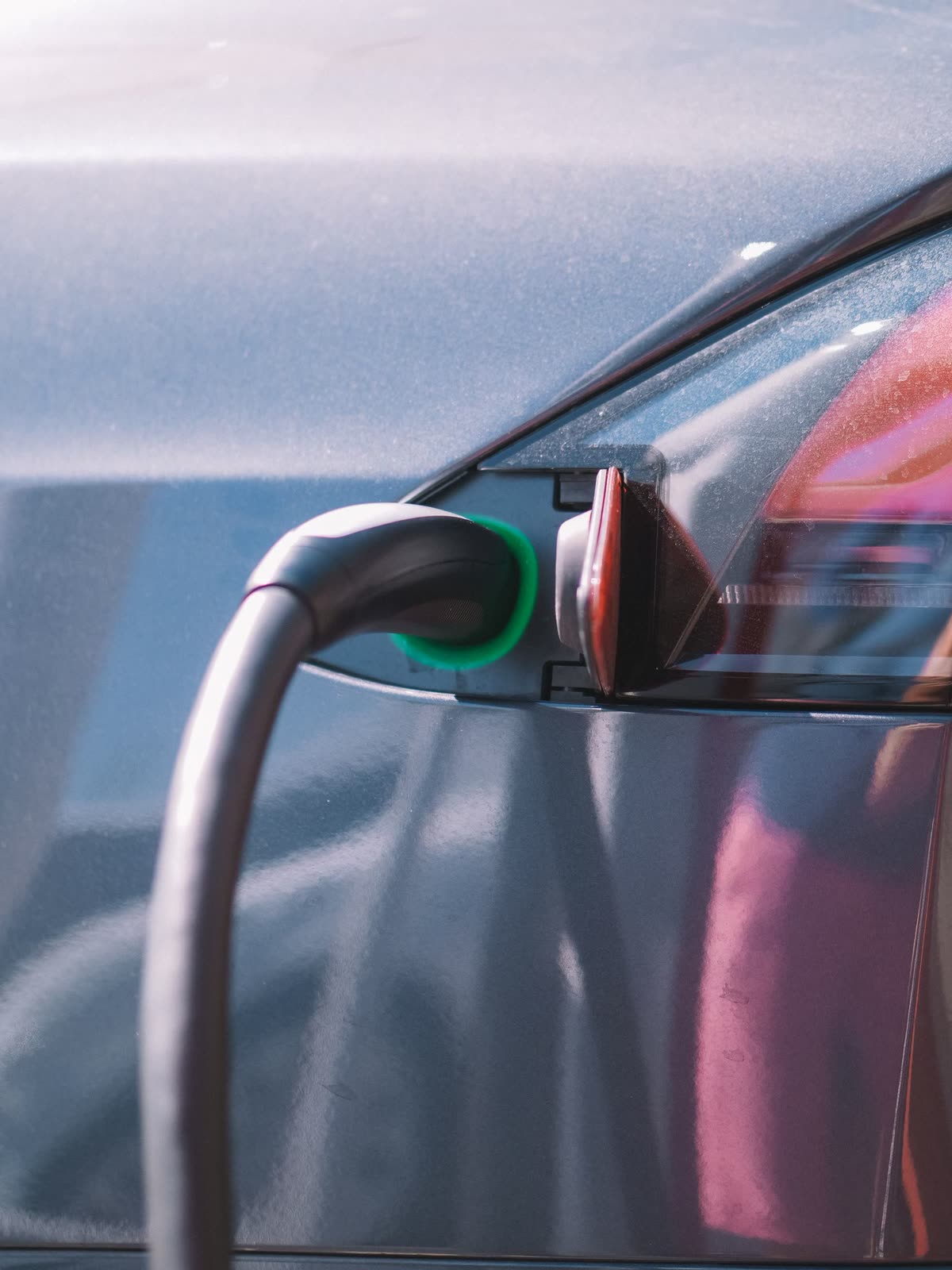 Cabo de carregamento conectado à entrada de um carro elétrico, com a luz verde acesa